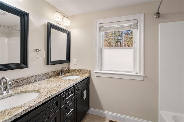 full bathroom featuring double vanity, baseboards, tile patterned floors, and a sink