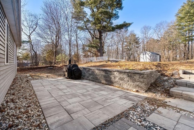 view of patio featuring an outbuilding, a storage shed, and fence