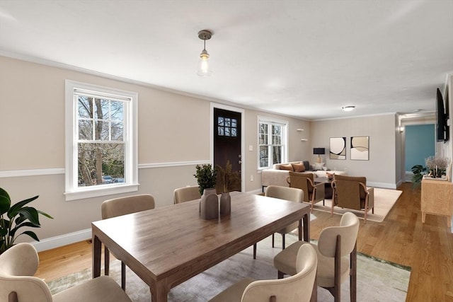 dining area with wood finished floors, baseboards, and ornamental molding