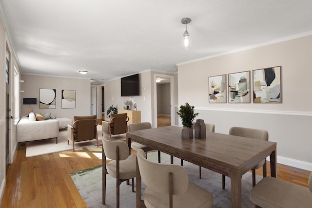 dining space with light wood-style floors, baseboards, and ornamental molding