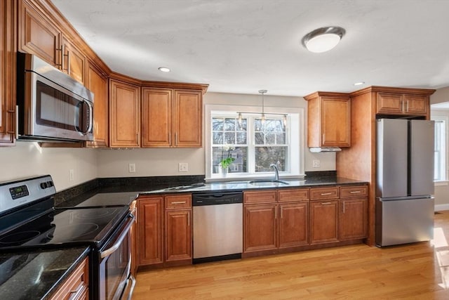 kitchen featuring a sink, brown cabinets, light wood finished floors, and stainless steel appliances