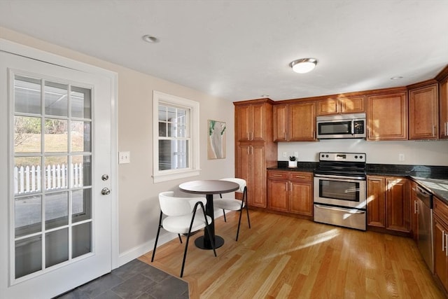 kitchen featuring dark countertops, light wood-type flooring, stainless steel appliances, and brown cabinetry