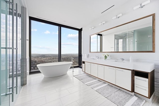 bathroom with tile patterned floors, expansive windows, a bath, and vanity