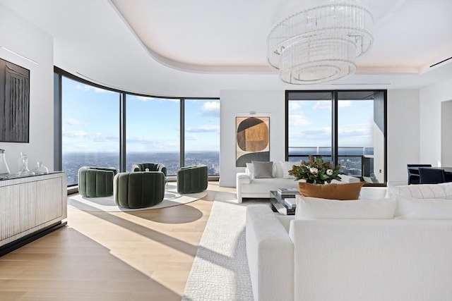 living room featuring a raised ceiling, a notable chandelier, plenty of natural light, and floor to ceiling windows