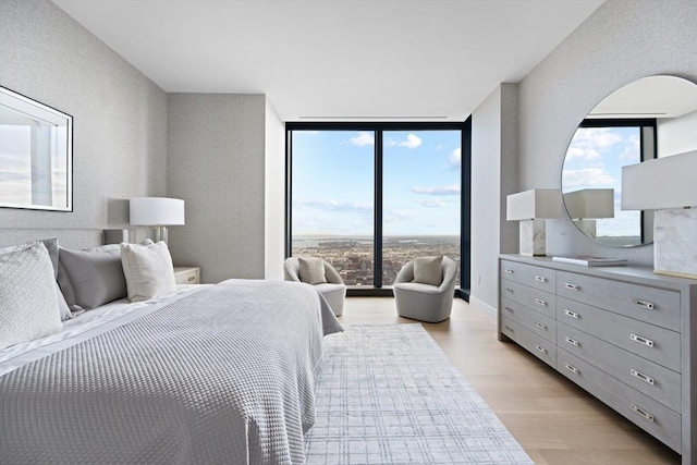 bedroom featuring expansive windows, access to exterior, and light hardwood / wood-style floors