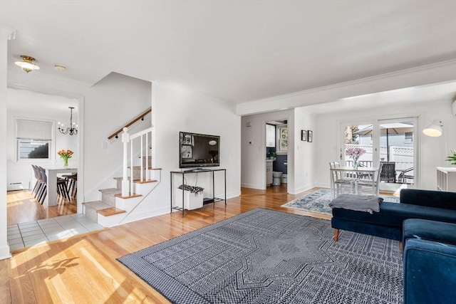 living room featuring a notable chandelier, a baseboard heating unit, stairs, and wood finished floors
