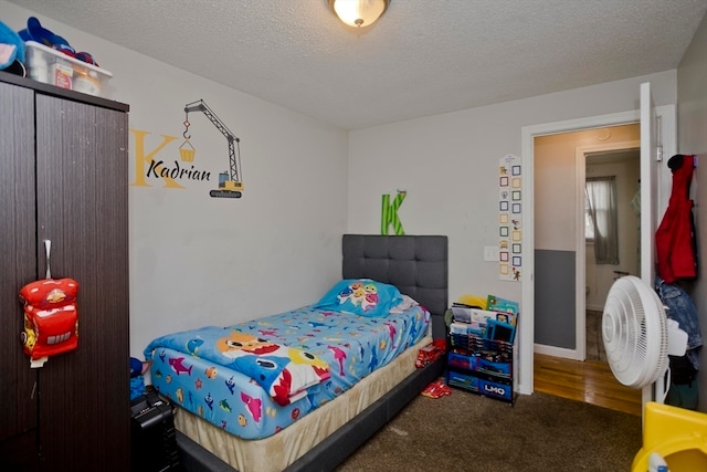 bedroom featuring dark colored carpet and a textured ceiling