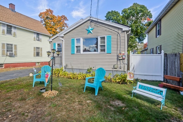 rear view of house with cooling unit and a lawn