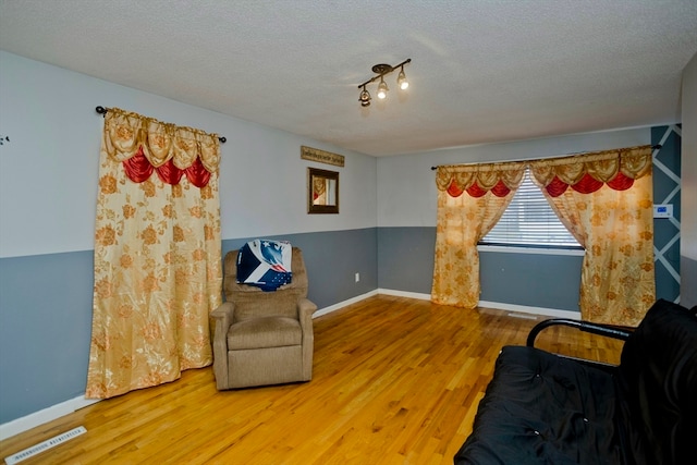 living area with a textured ceiling and hardwood / wood-style floors