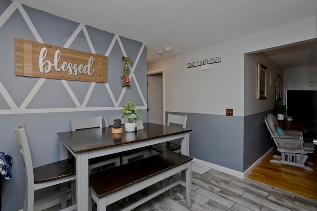 dining space with wood-type flooring and a textured ceiling