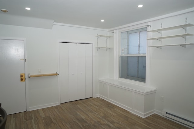 spacious closet featuring dark wood-type flooring and a baseboard heating unit