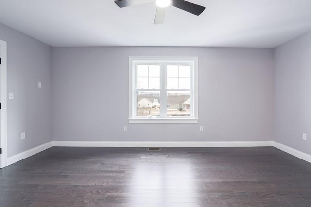 empty room with a ceiling fan, visible vents, dark wood finished floors, and baseboards