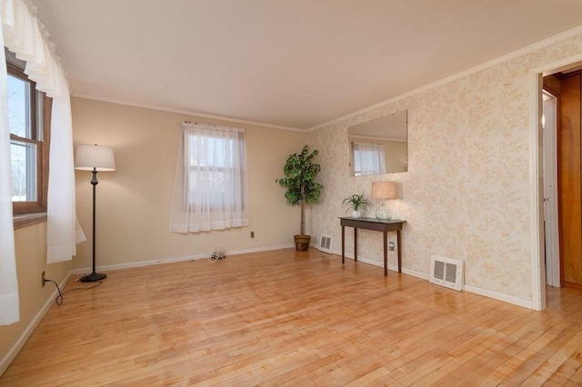 unfurnished room featuring baseboards, visible vents, light wood finished floors, and ornamental molding