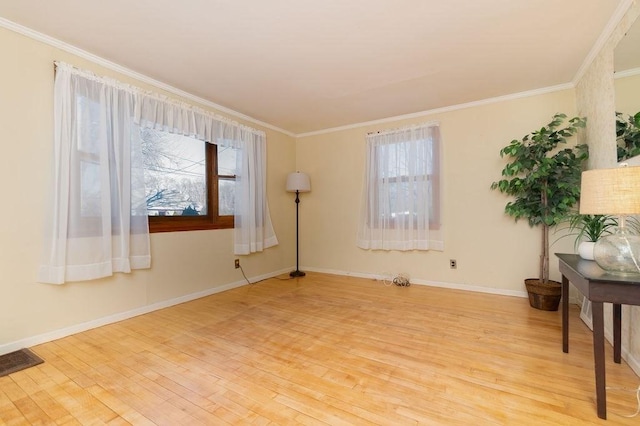 empty room with visible vents, crown molding, light wood-type flooring, and baseboards