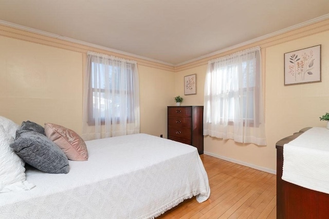 bedroom featuring baseboards, light wood-style floors, and ornamental molding