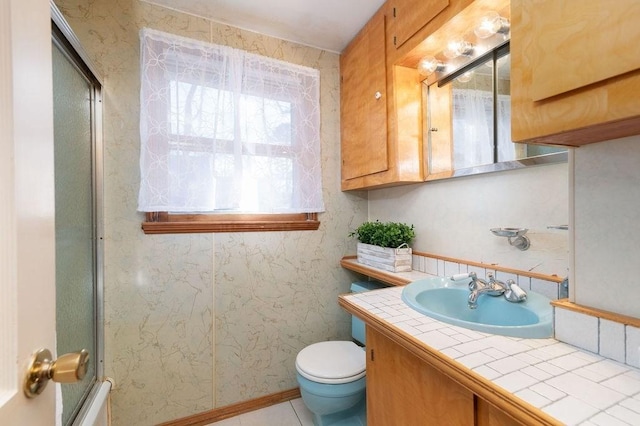 bathroom featuring an enclosed shower, toilet, vanity, and wallpapered walls