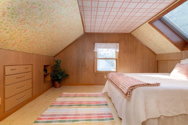 bedroom featuring lofted ceiling with skylight and wood walls