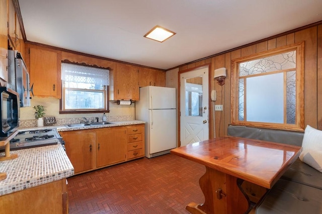 kitchen with brown cabinets, white appliances, light countertops, and a sink