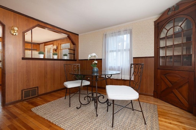 dining room featuring visible vents, wainscoting, ornamental molding, and wood finished floors