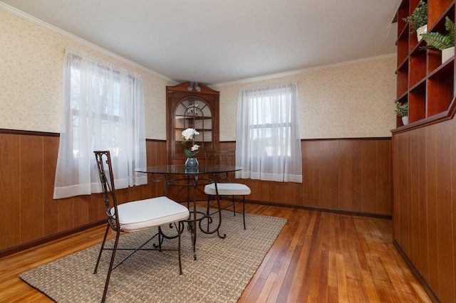 dining area featuring a wainscoted wall, hardwood / wood-style floors, and wallpapered walls