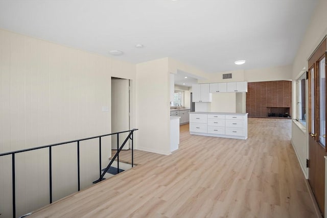 unfurnished living room featuring a fireplace, light wood-style floors, and a sink