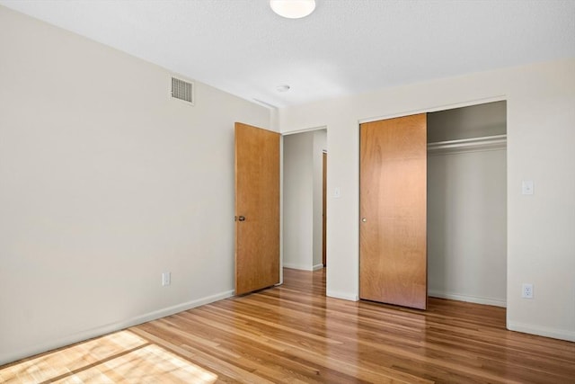 unfurnished bedroom with wood finished floors, a closet, and baseboards