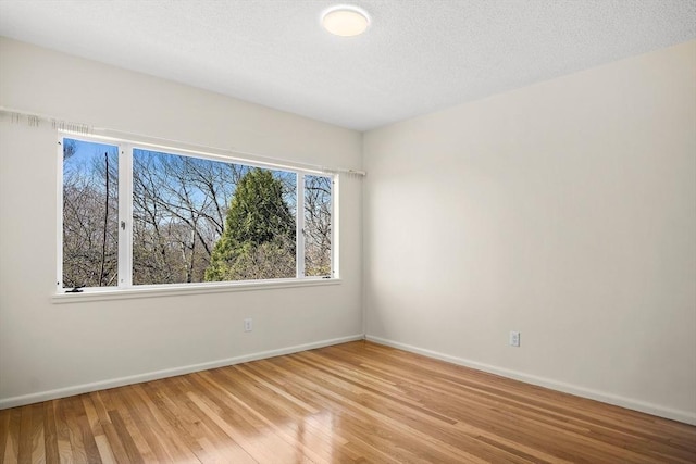unfurnished room with light wood-style flooring, baseboards, and a textured ceiling