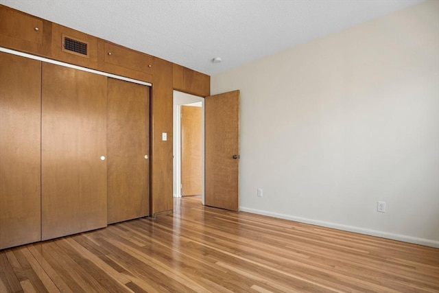 unfurnished bedroom featuring light wood-style flooring, a closet, and baseboards