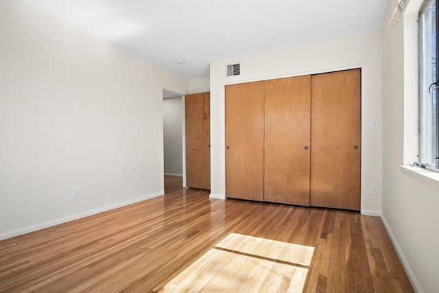 unfurnished bedroom with wood finished floors, a closet, and baseboards