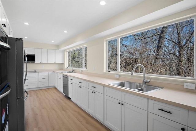 kitchen featuring a sink, appliances with stainless steel finishes, light wood-type flooring, white cabinets, and recessed lighting