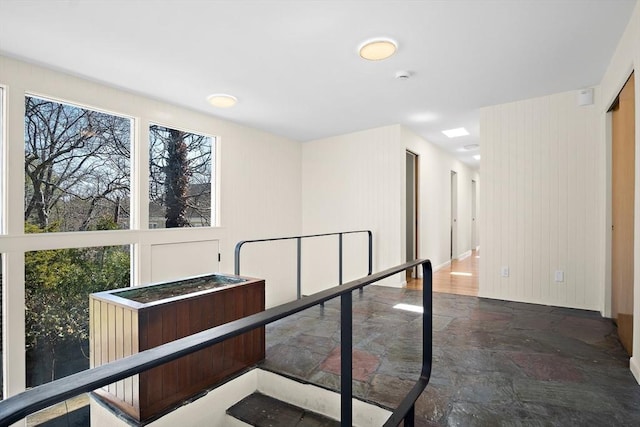 corridor with plenty of natural light and stone finish flooring