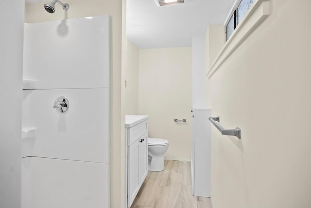 bathroom with a shower, vanity, wood finished floors, and toilet