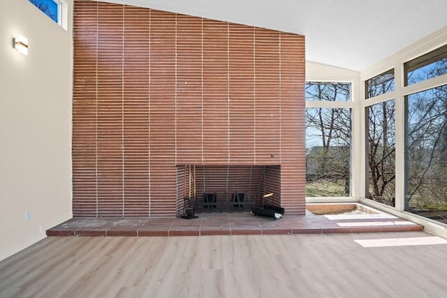 unfurnished living room featuring wood finished floors, a tile fireplace, and lofted ceiling