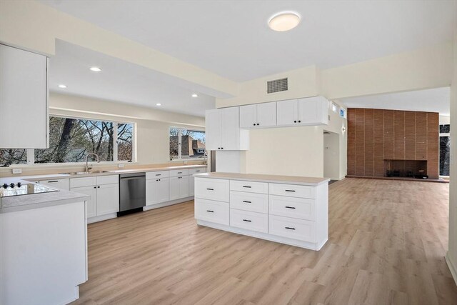 kitchen with a sink, stainless steel dishwasher, light wood-type flooring, black electric cooktop, and white cabinetry