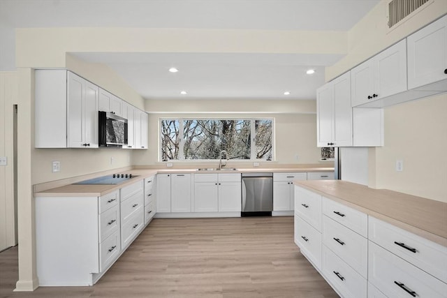 kitchen featuring stainless steel appliances, a sink, light countertops, light wood-type flooring, and white cabinets