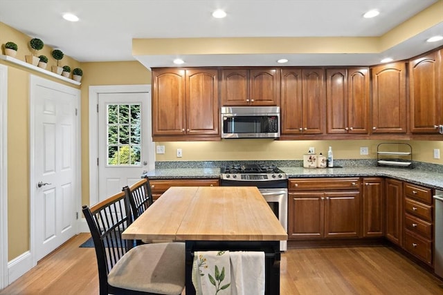 35 Harvard St, Winchester, MA 01890 - kitchen with appliances with stainless steel finishes, light wood-type flooring, light stone counters, recessed lighting, and brown cabinets