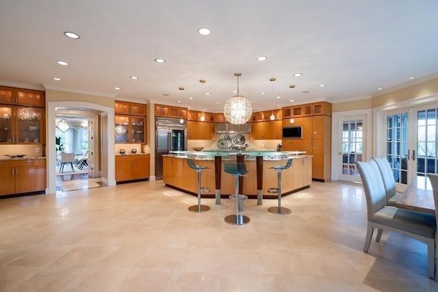 kitchen with built in appliances, pendant lighting, a spacious island, french doors, and a kitchen breakfast bar