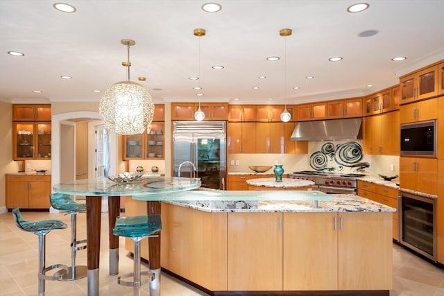 kitchen featuring built in appliances, light stone countertops, pendant lighting, a spacious island, and wine cooler