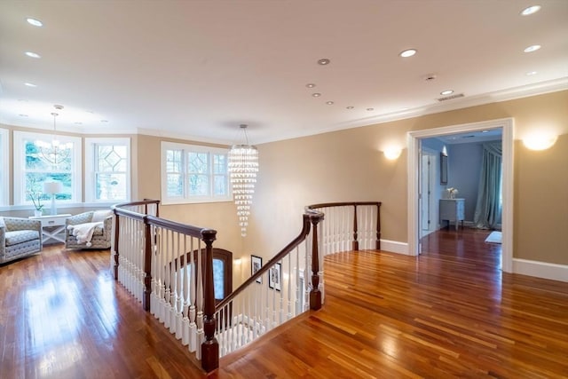 corridor with a notable chandelier, crown molding, and hardwood / wood-style flooring