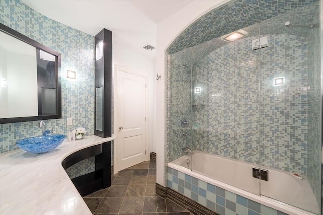 bathroom with shower / bath combination with glass door, tile patterned floors, tile walls, and vanity