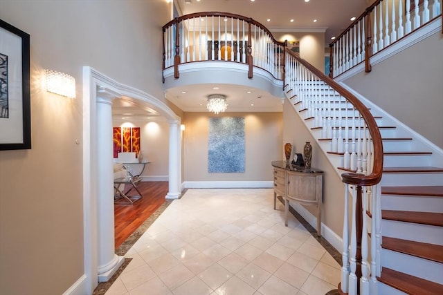 tiled entrance foyer featuring a towering ceiling and decorative columns