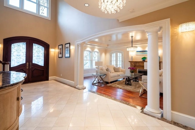 entryway with crown molding, french doors, light tile patterned flooring, and a chandelier