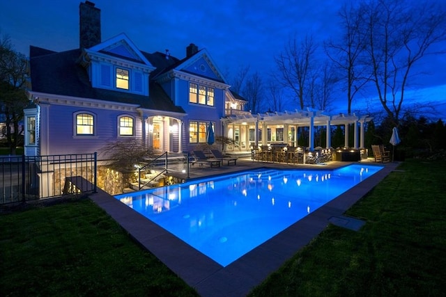 pool at night with a pergola, a yard, and a patio