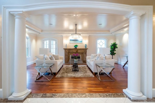 living room featuring a premium fireplace, a raised ceiling, and ornamental molding