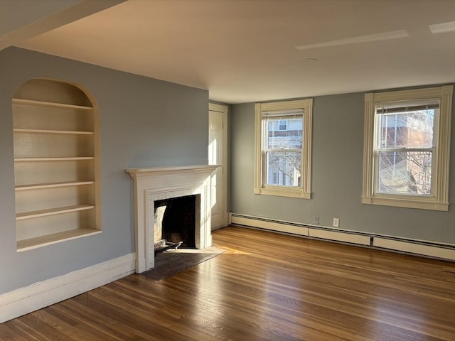 unfurnished living room with built in features, a baseboard heating unit, a fireplace with flush hearth, wood finished floors, and baseboards