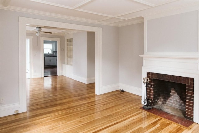 unfurnished living room with ceiling fan, built in shelves, light wood-style flooring, a fireplace with flush hearth, and baseboards