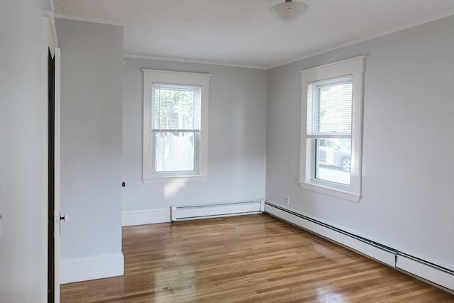 empty room featuring crown molding, a baseboard radiator, baseboard heating, wood finished floors, and baseboards