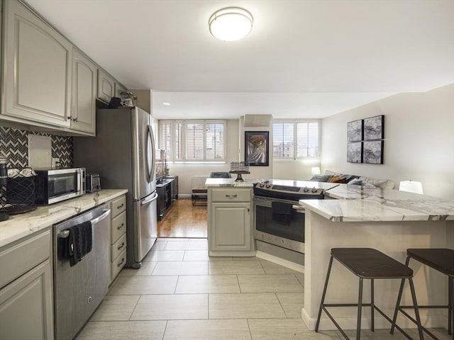 kitchen with appliances with stainless steel finishes, a kitchen bar, and a center island