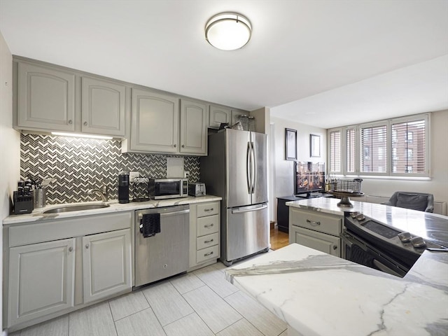 kitchen with stainless steel appliances, light stone countertops, and backsplash