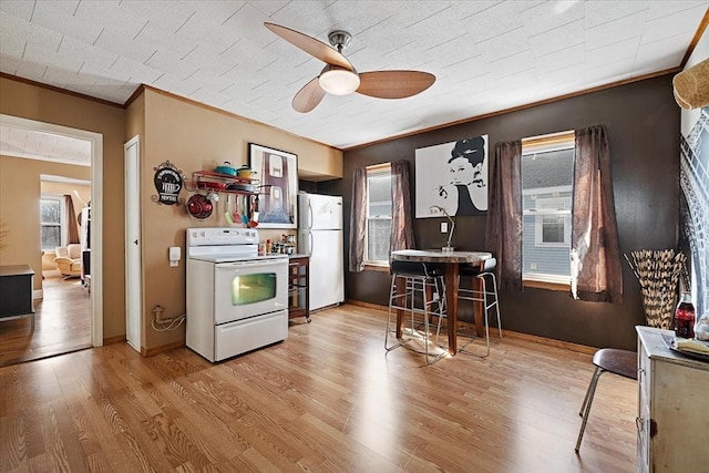 kitchen featuring white appliances, a ceiling fan, baseboards, light wood finished floors, and crown molding